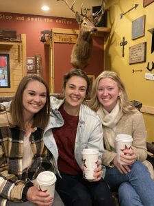 three woman smiling at a coffee shop