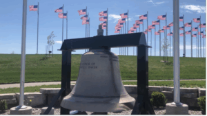 liberty bell and flags at a soldier monument 